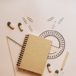 An organized flat lay of school supplies including a notebook, pencils, and paper clips.