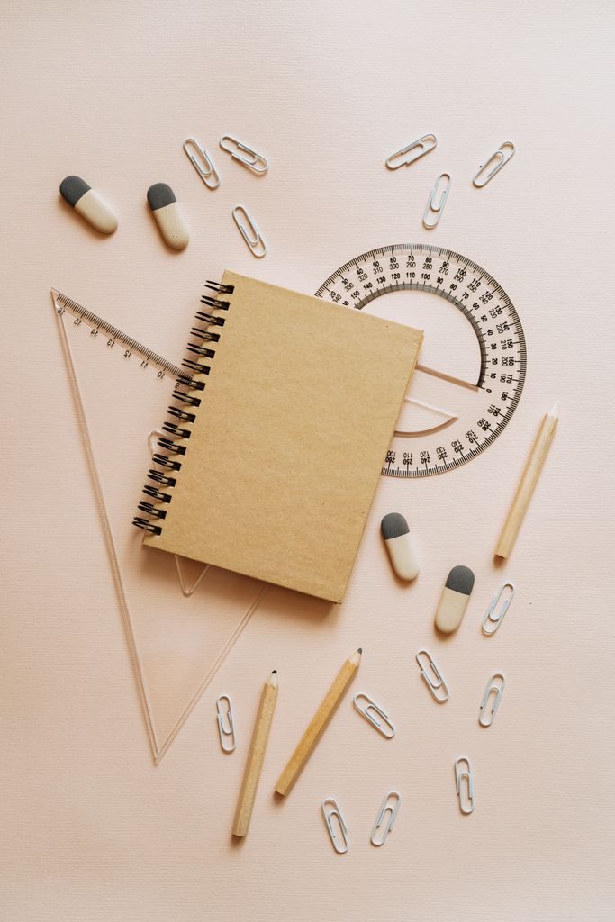 An organized flat lay of school supplies including a notebook, pencils, and paper clips.